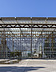 Photo of a large building made of glass and steel girders with a large concrete forecourt