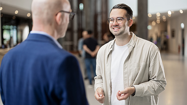 Man and woman sitting at a table with a laptop, tablet and two cell phones in front of them.