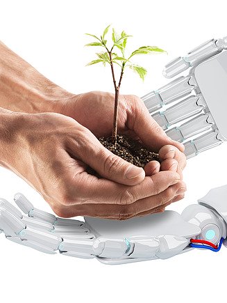 Image of two robotic hands and two human hands with soil and a plant growing in them