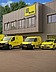 Photo of a fleet of yellow vehicles in front of a building