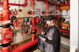 Photo of employee standing at a sprinkler system and looking into a tablet