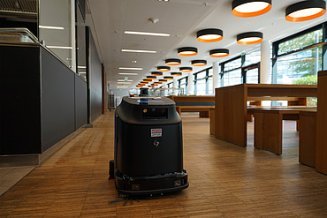 Foto von einem Reinigungsroboter in einem großem Raum mit Tischen